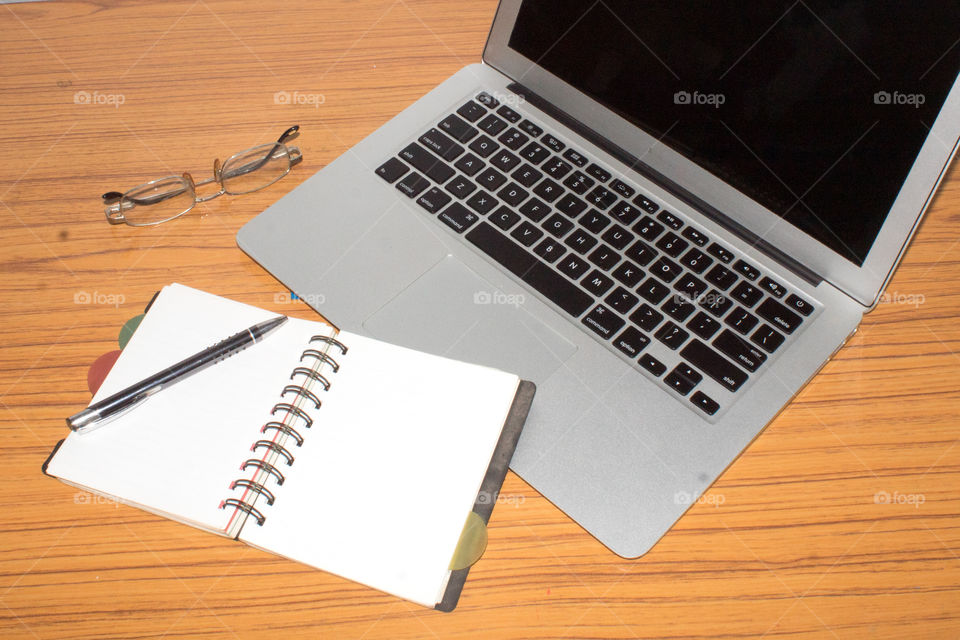 Desk with open notepad, pen, eye glasses, nicely placed on office table. Top view with copy space. Business still life concept with office stuff on table. Education, working or planning concept