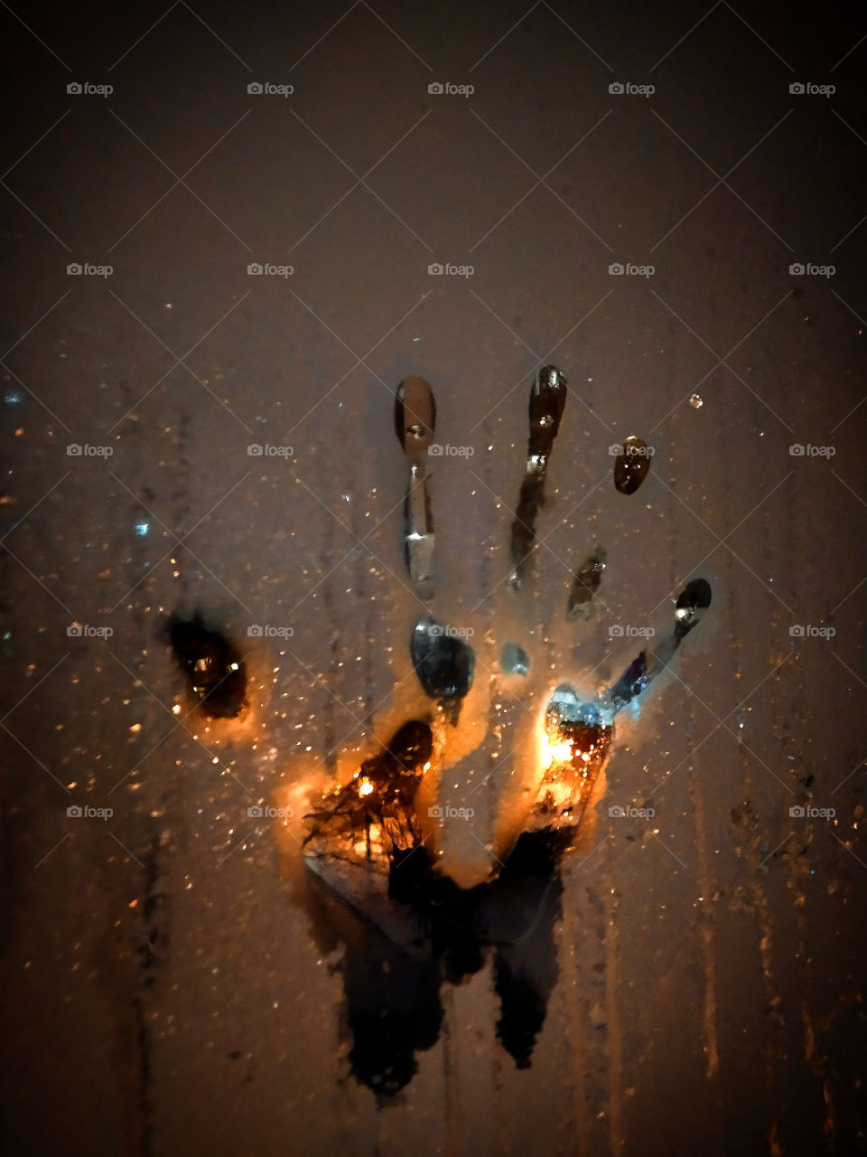 Palm print on frozen glass against the backdrop of street lamps