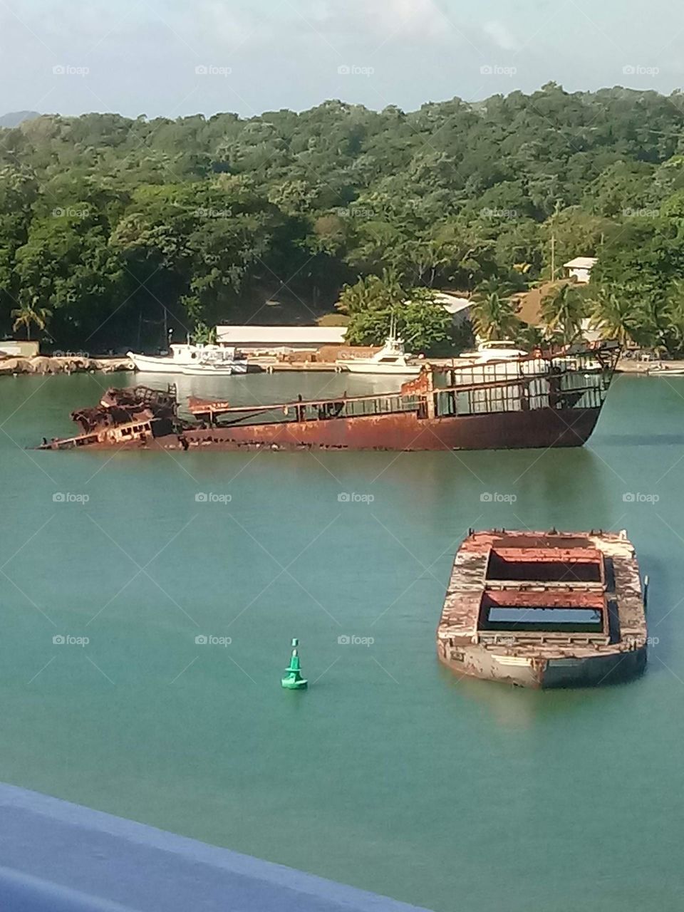 Sunken broken rusted ships in the bay in the green ocean in Belize 