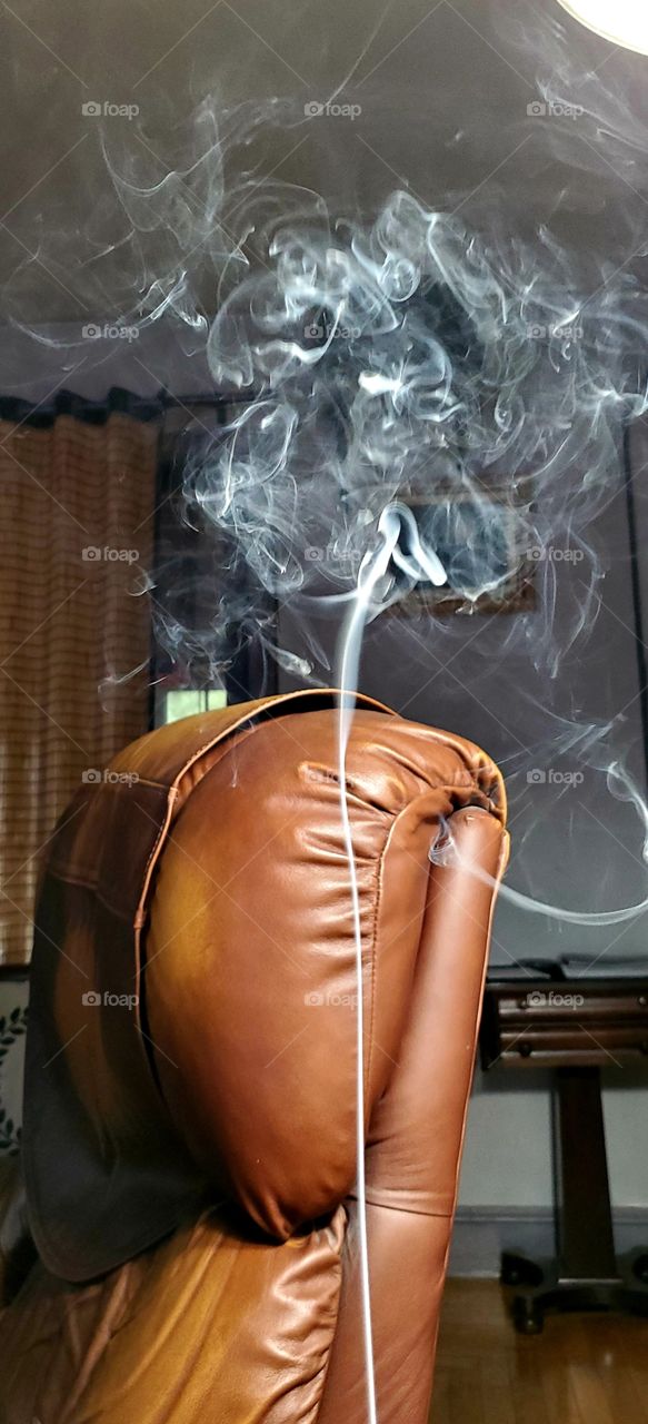 Smoke stream from ashtray,  awesome effect into the air. Contrast of white against brown leather chair going into the still air.