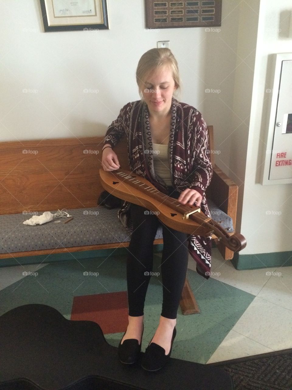A teenage girl plays music on a beautiful antique mountain dulcimer for her onlooking friends