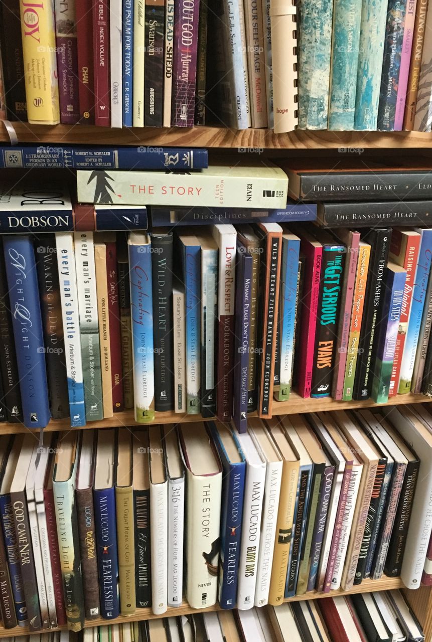 Books on an old shelf await new owners. The shelves are stuffed full of books.