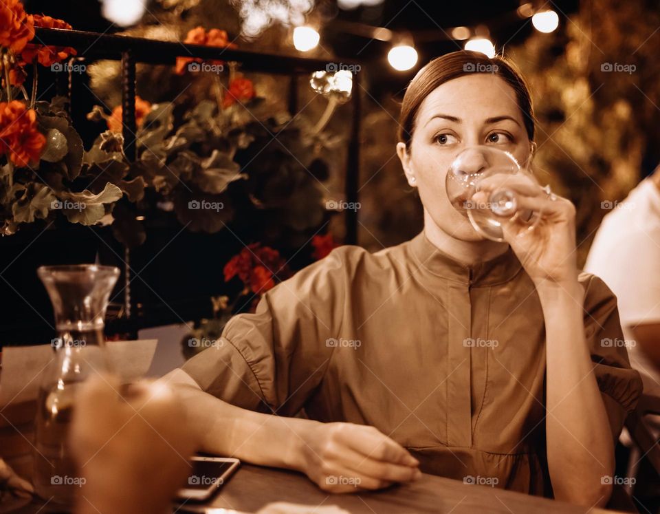 young adult woman with a glass of some drink at restaurant