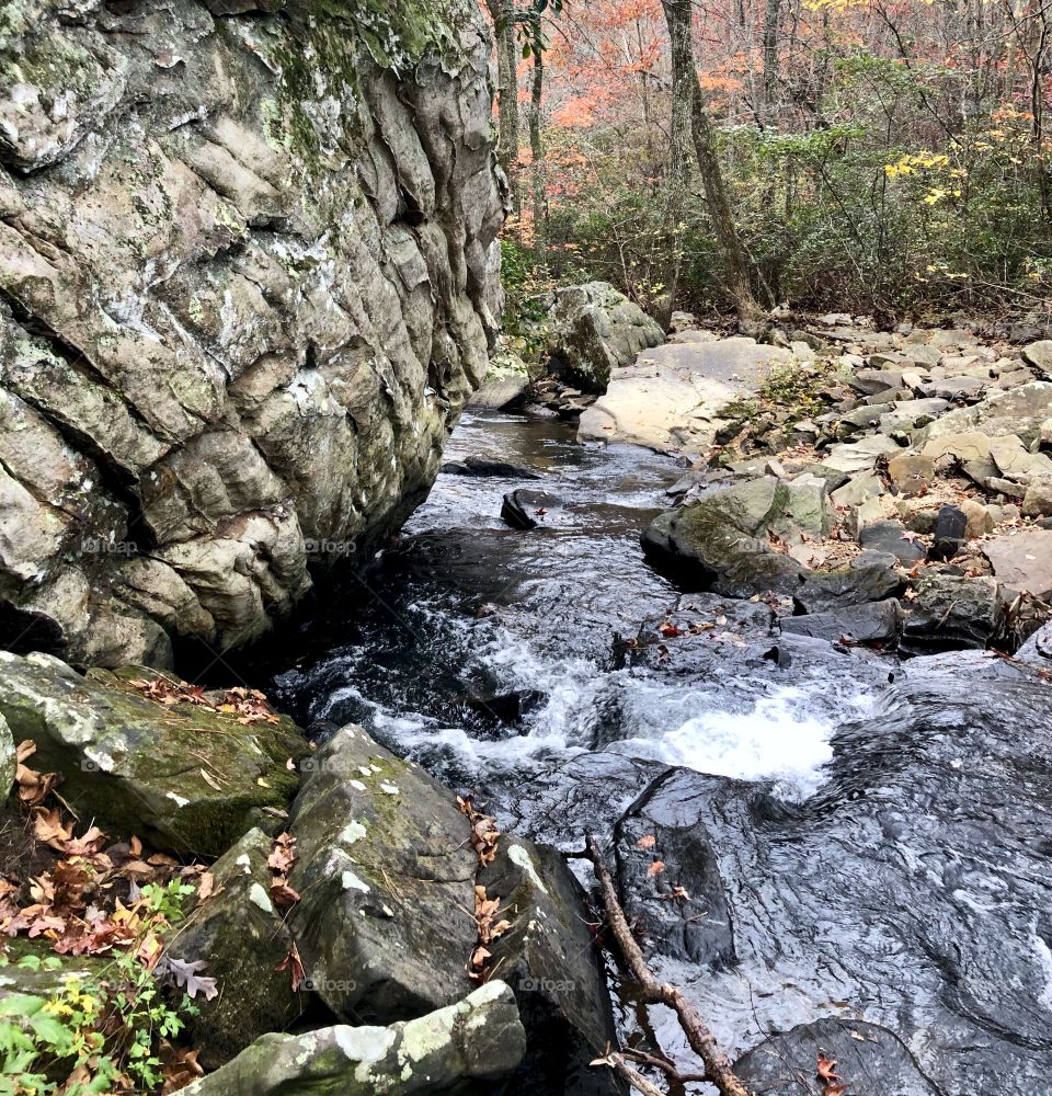 Fast flowing mountain stream rushing around boulders in forest 