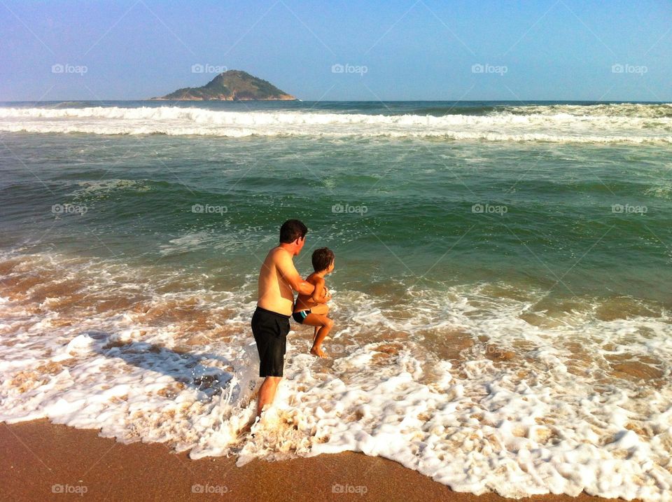 Father and son at the beach playing in the water. 