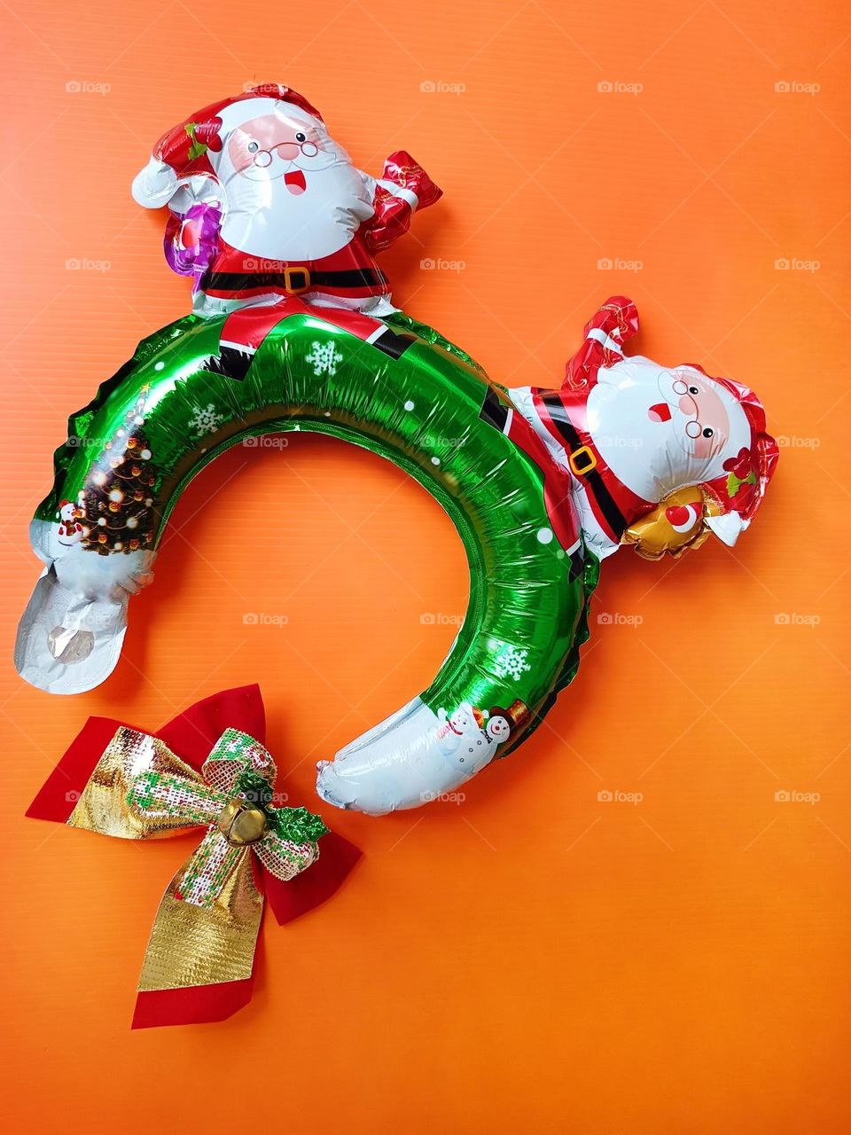 Santa Claus Christmas headband and Christmas bow on orange background vertical composition.