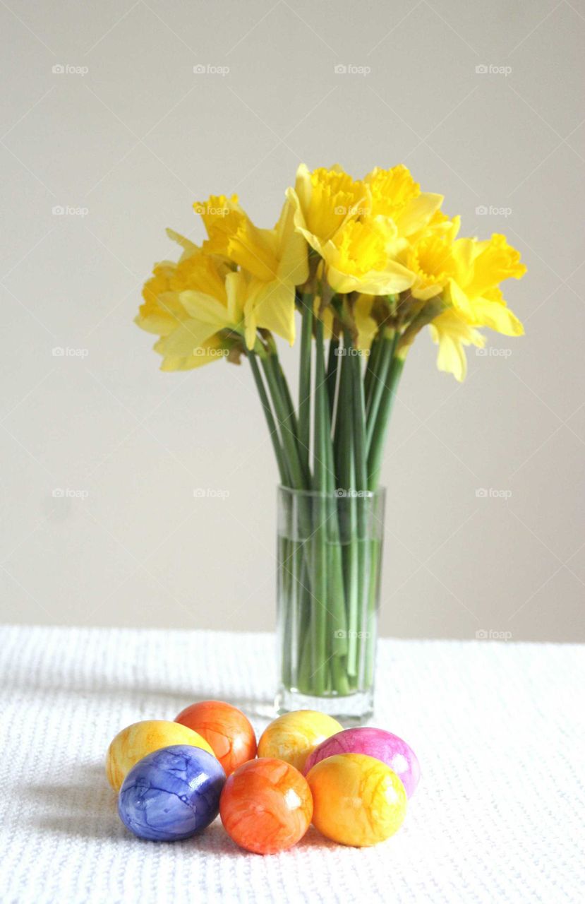 Easter eggs and vase of yellow flowers on table