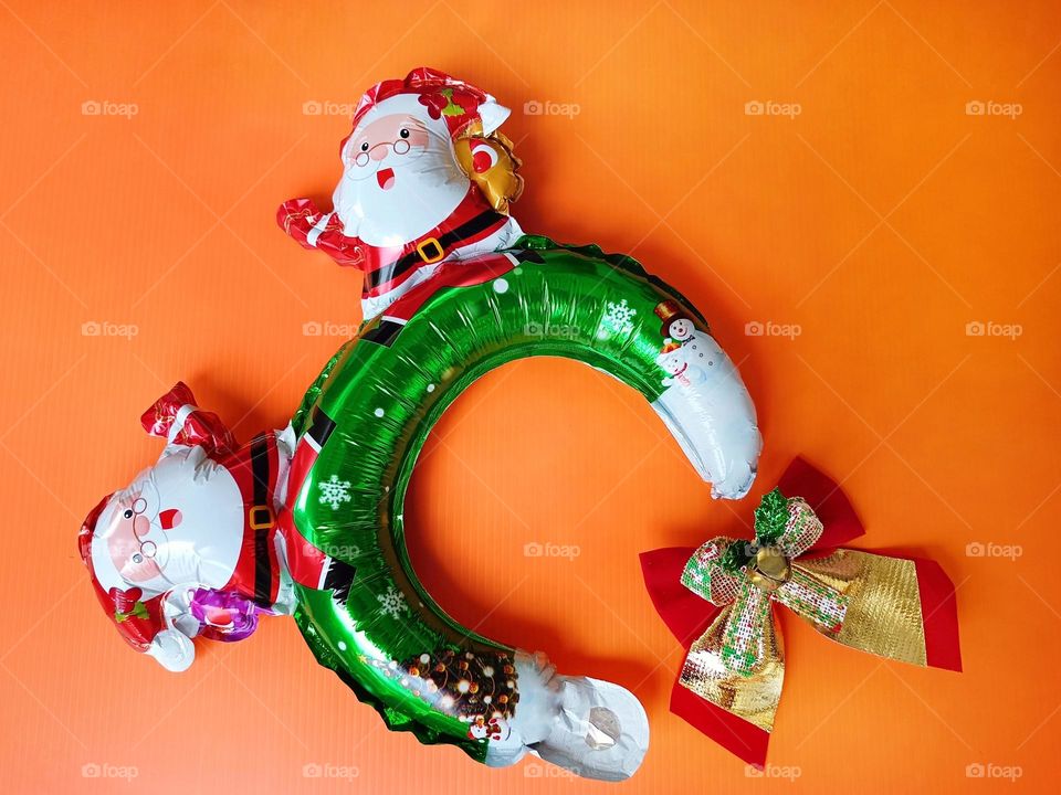 Santa Claus headband and Christmas bow on orange background horizontal composition.