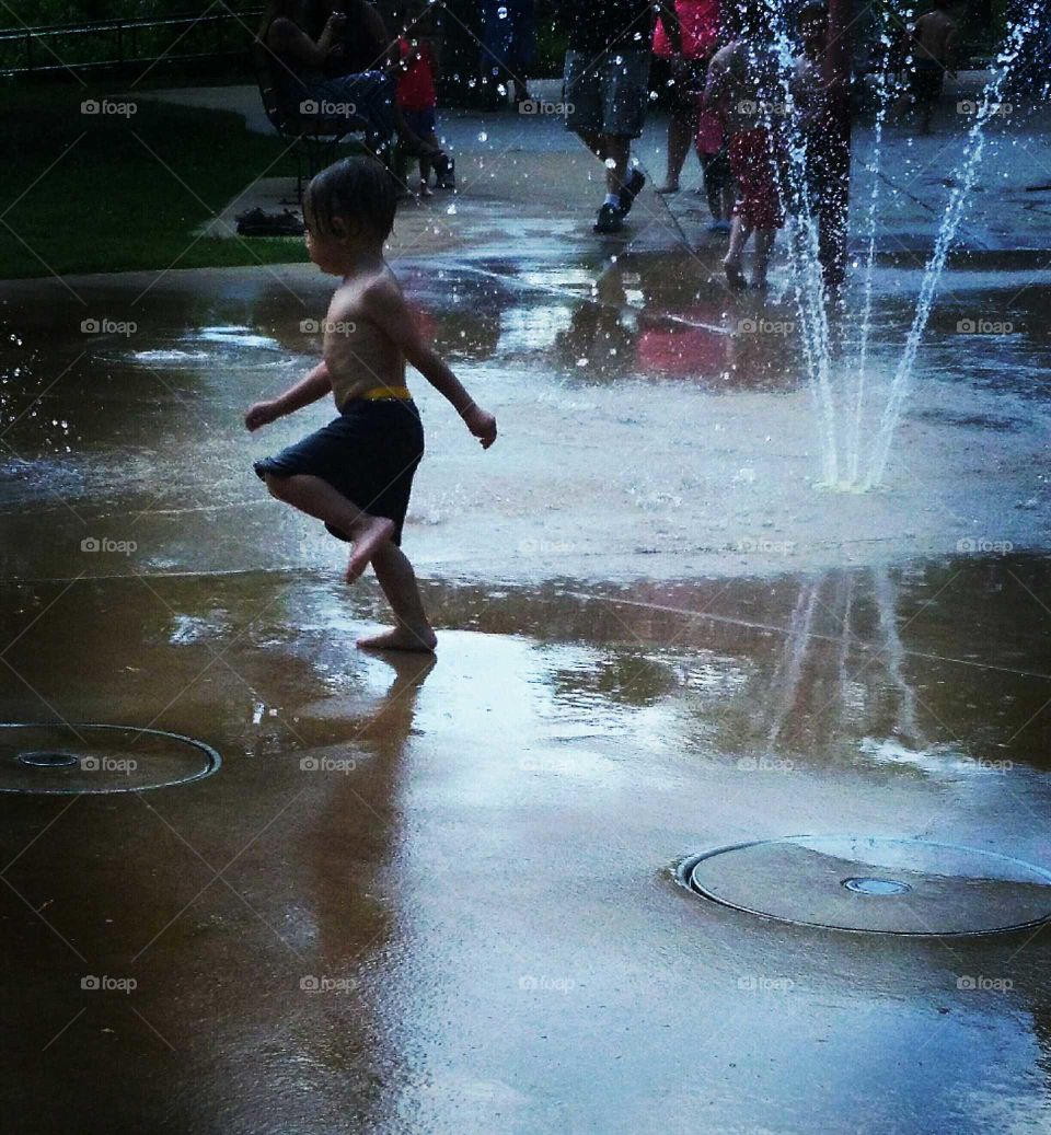 child running through sprinkler