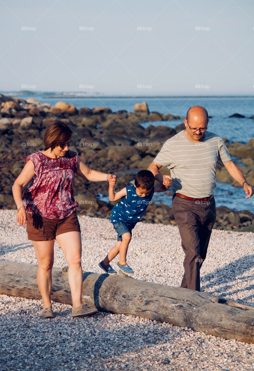 Grandparents enjoying a walk on the beach with grandson 