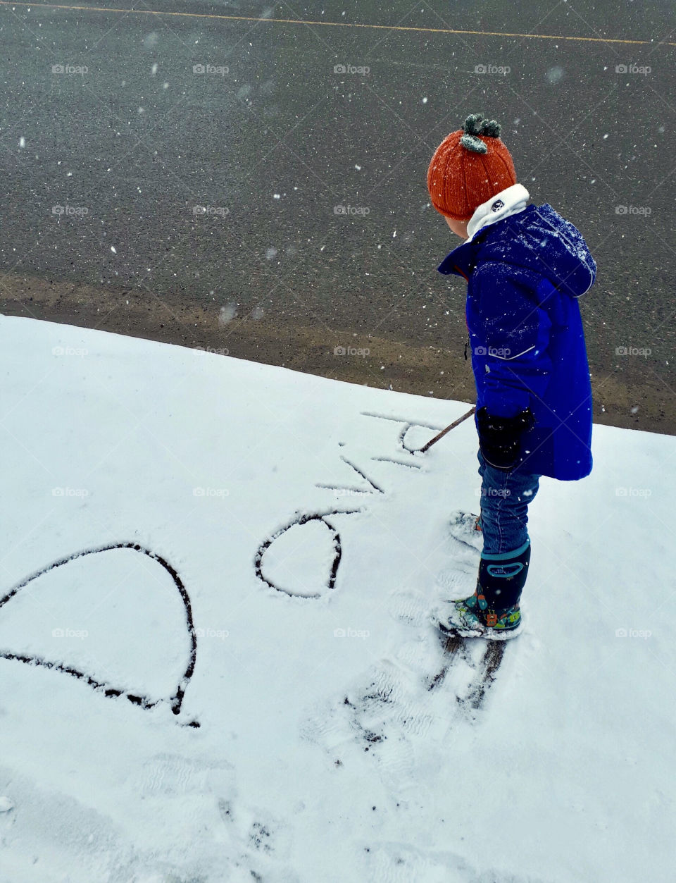 Young boy writing his name in the snow