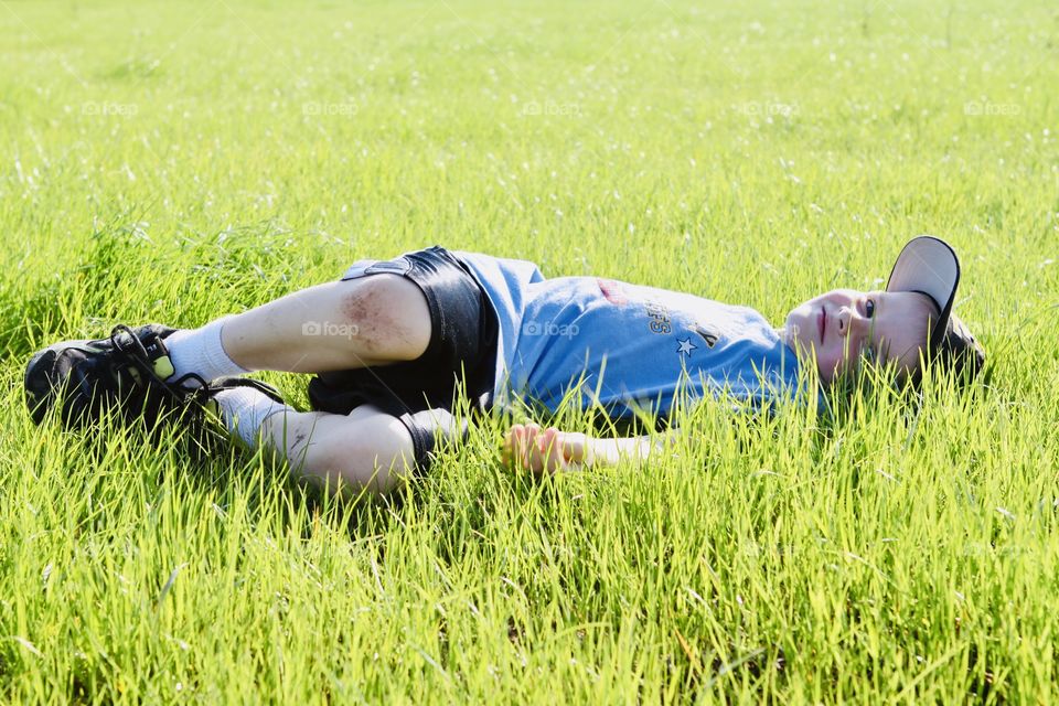Darling photo of young boy laying in tall grass after playing some ball with his Daddy! 