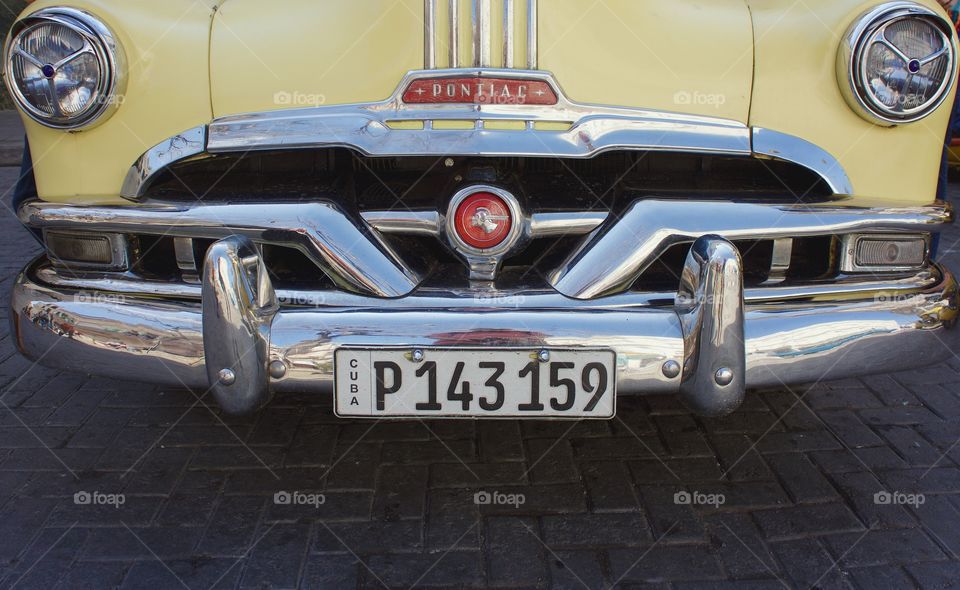 A closeup front view of the old yellow Pontiac taxi parked on the street in Old Havana, Cuba.