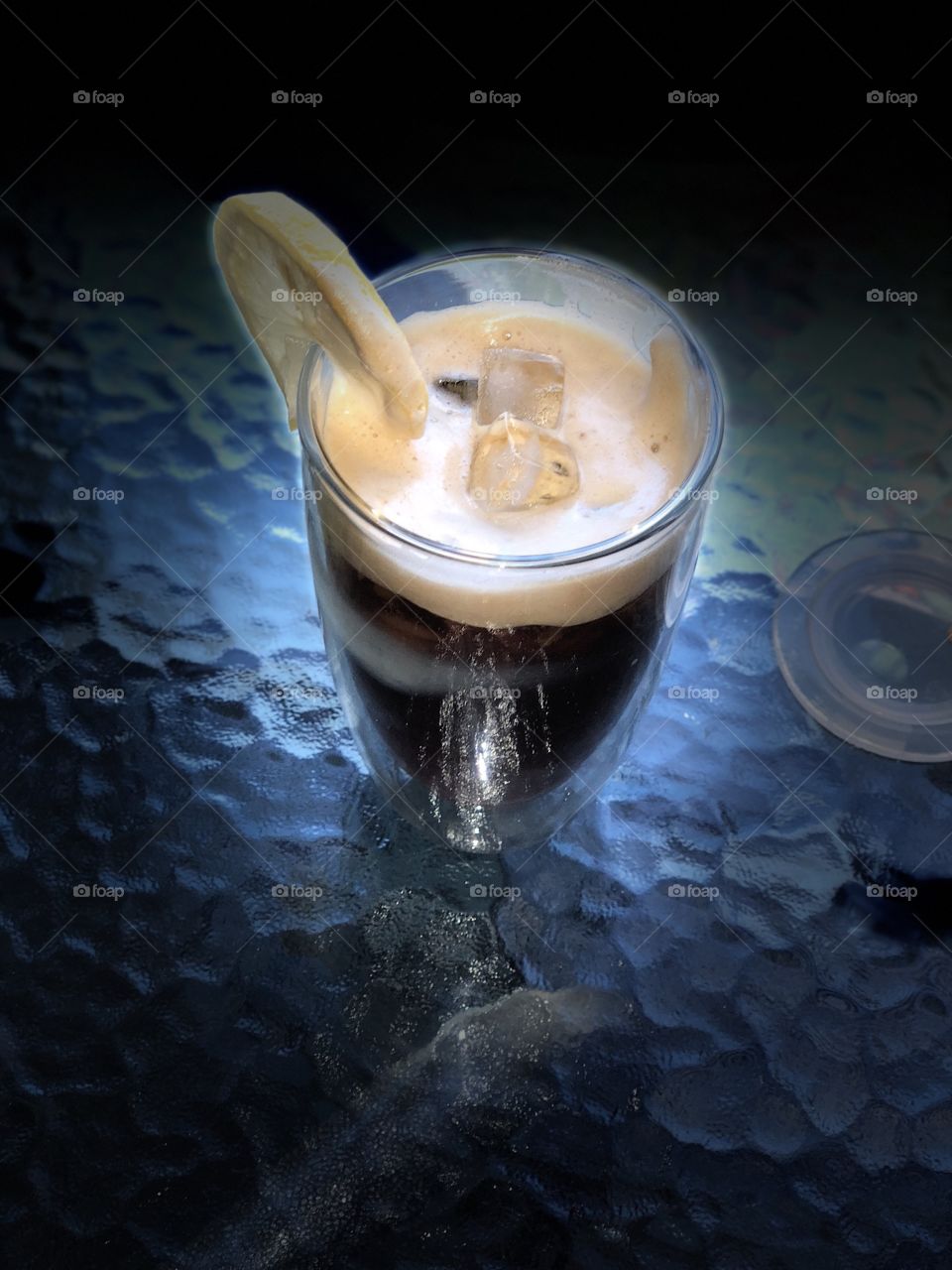 A glass of Ice coffee with a lemon cut