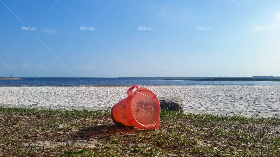 kiddie pail on the grass, sand and water on the background infinite fun