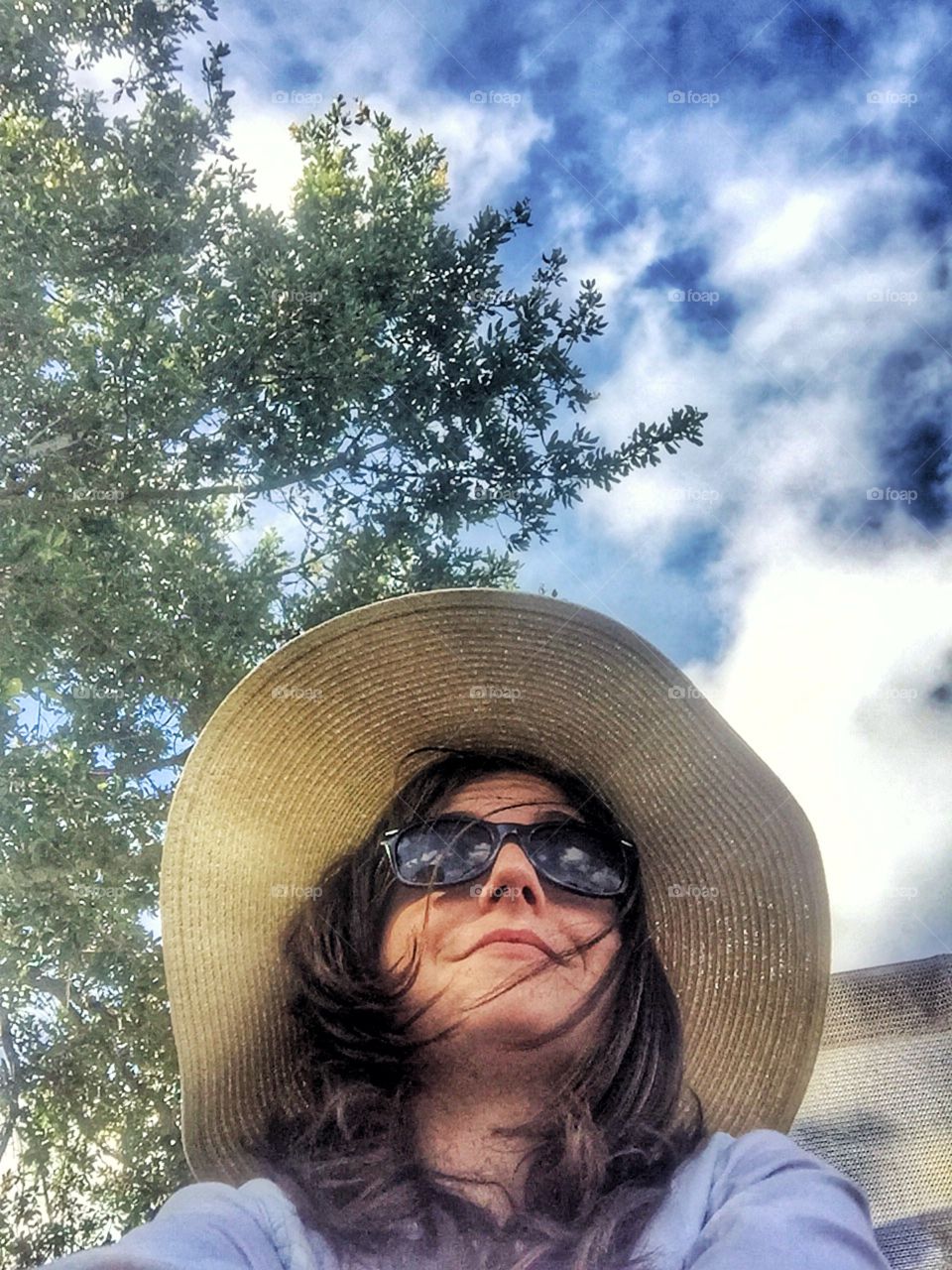 A woman in a sun hat looking at the sky 