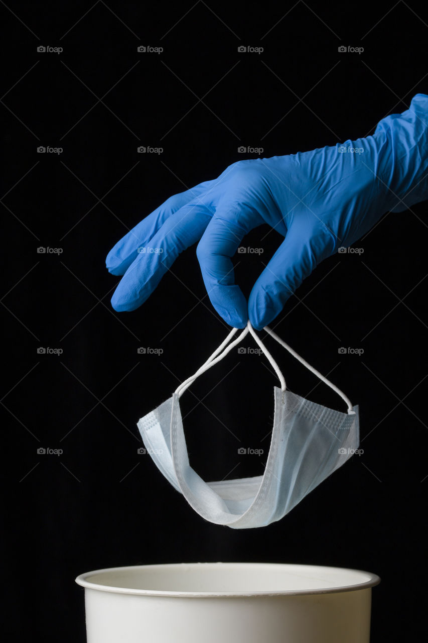 medical protective mask and doctor's hand on black background.