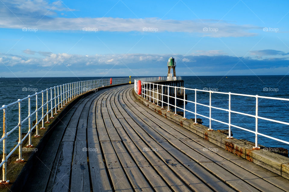 Traditional curved wood pier with lighthouse 