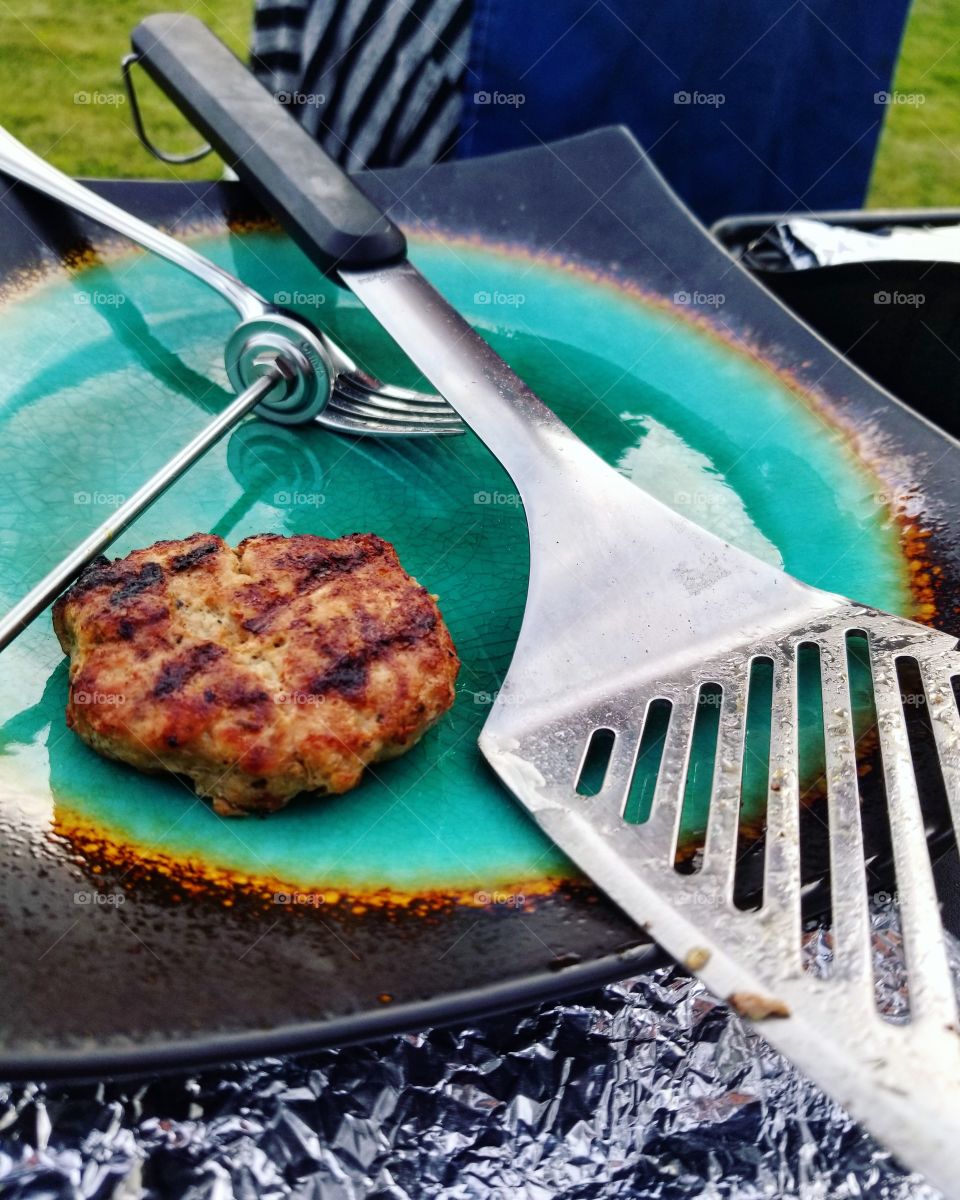 Grilled Turkey Burger Patty on a teal plate next to a metal spatula at a summer cookout