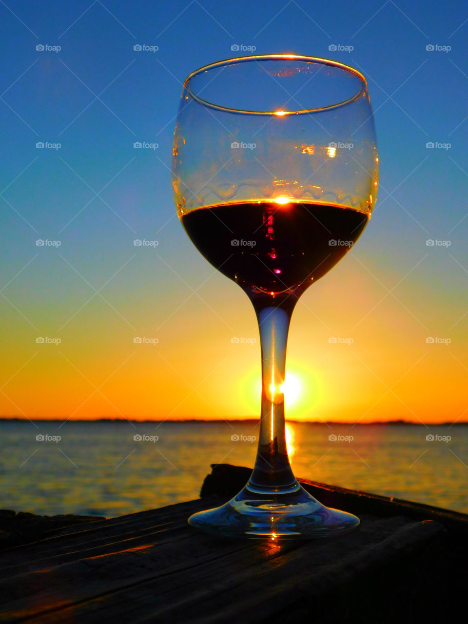 A Glass of wine on table at sea during sunset