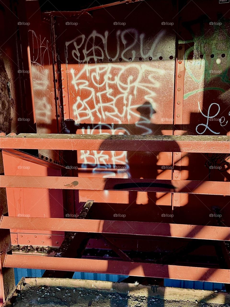 This is the red metal staircase of the „Pulaski Bridge“ at „Newtown Creek“ in LIC, Queens. The warm light of the setting sun turns it aglow and casts interesting shadows upon it as in the image of myself, the photographer. 2024. Hypnotic Productons