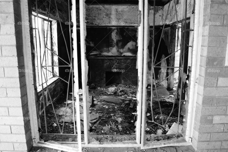 Look of a burned house through the broken windows and a fireplace inside