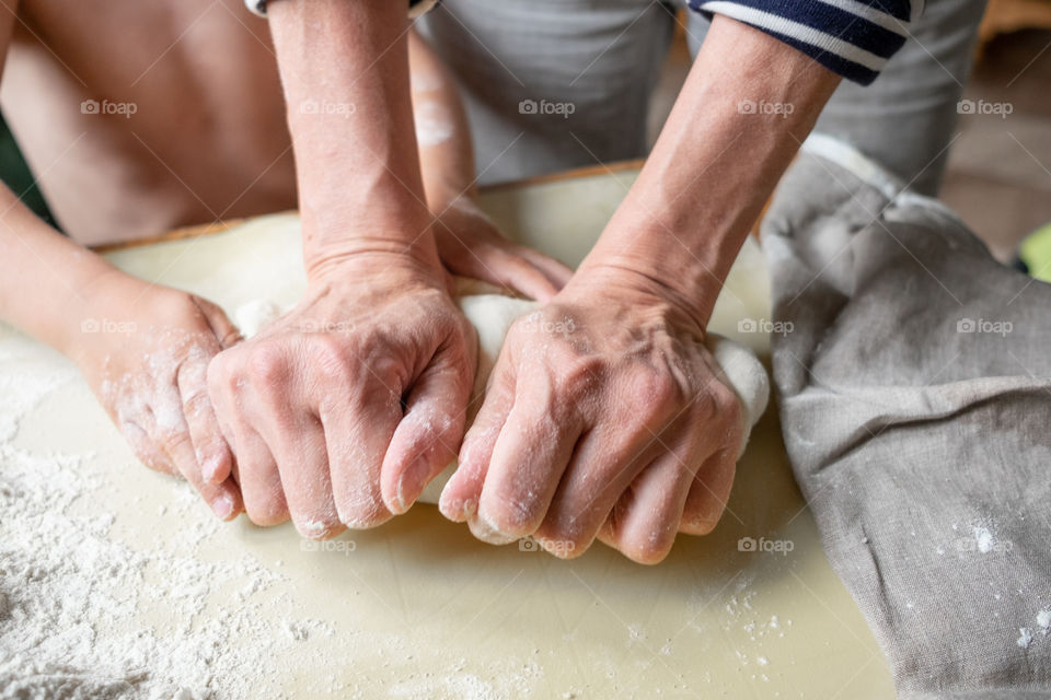 Adult and kids hands making dough for pastry together