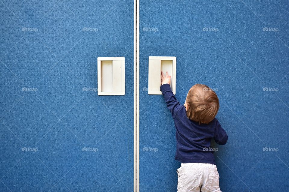 Toddler boy trying to open blue door 