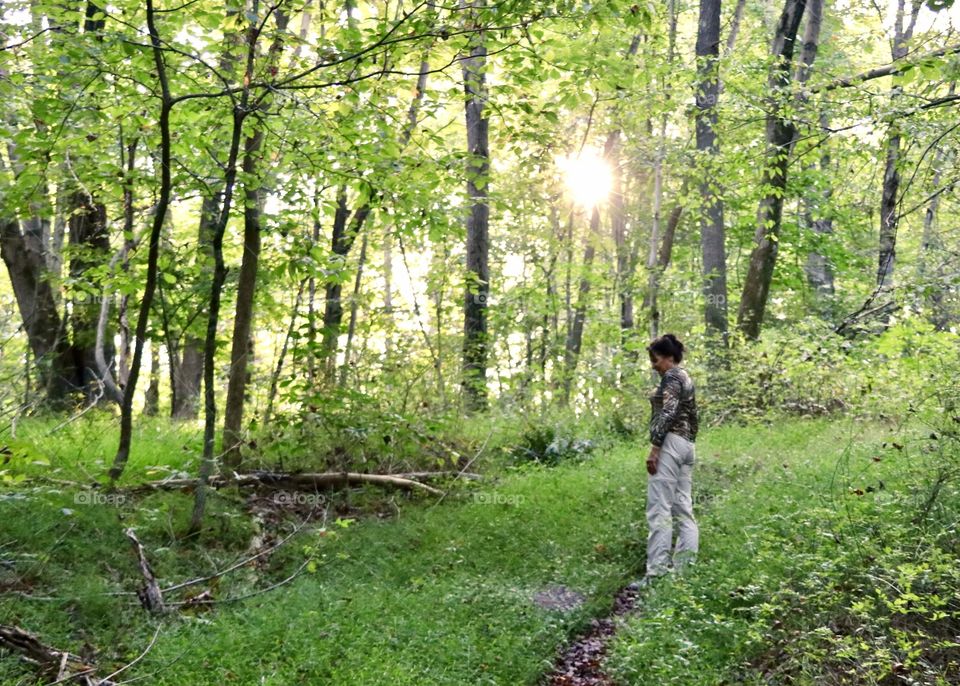 Woman in the forest as evening sun peeks through the trees