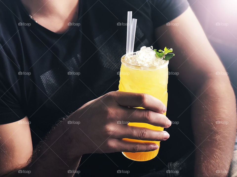 Young man enjoying cold summer tropical cocktail 