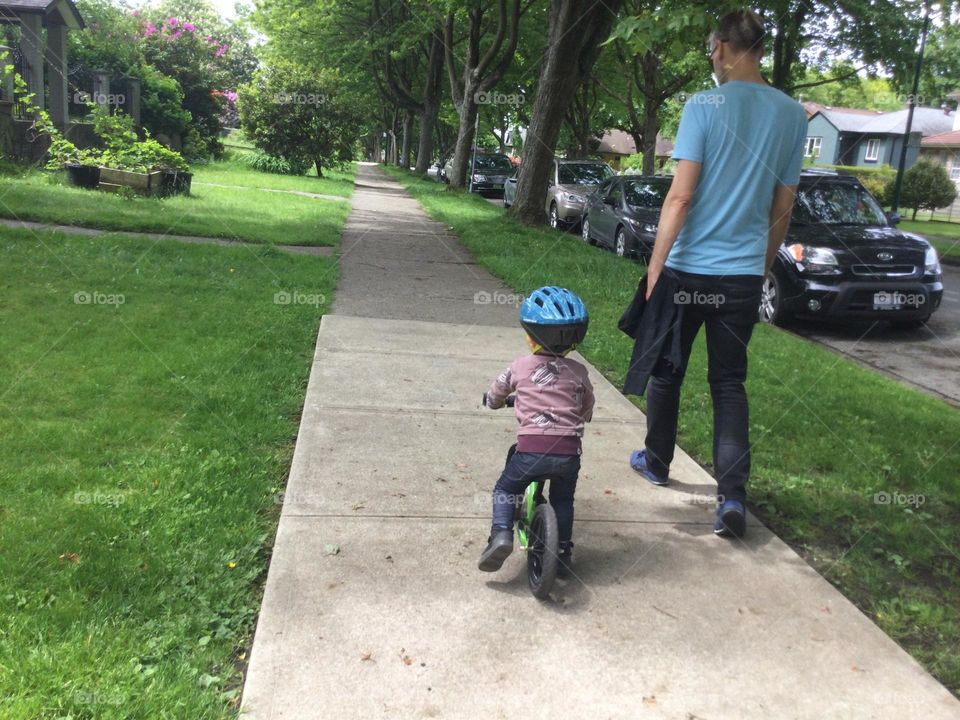 A little boy on a bike with his dad