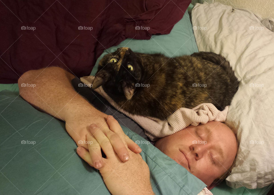 A man sleeping next to a cat.