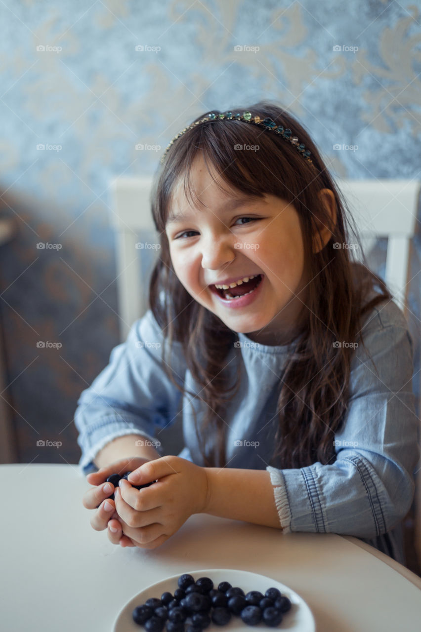 Smiling Little girl with blueberries at morning 