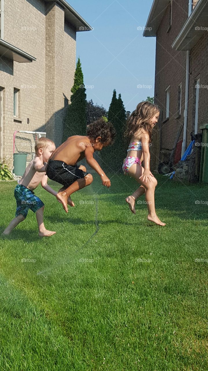 kids playing in sprinkler on summer day