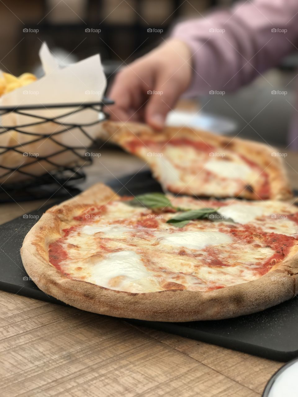 
Fresh Italian pizza on a wood table. Delicious Pizza Margherita.  Taking a slice of pizza 