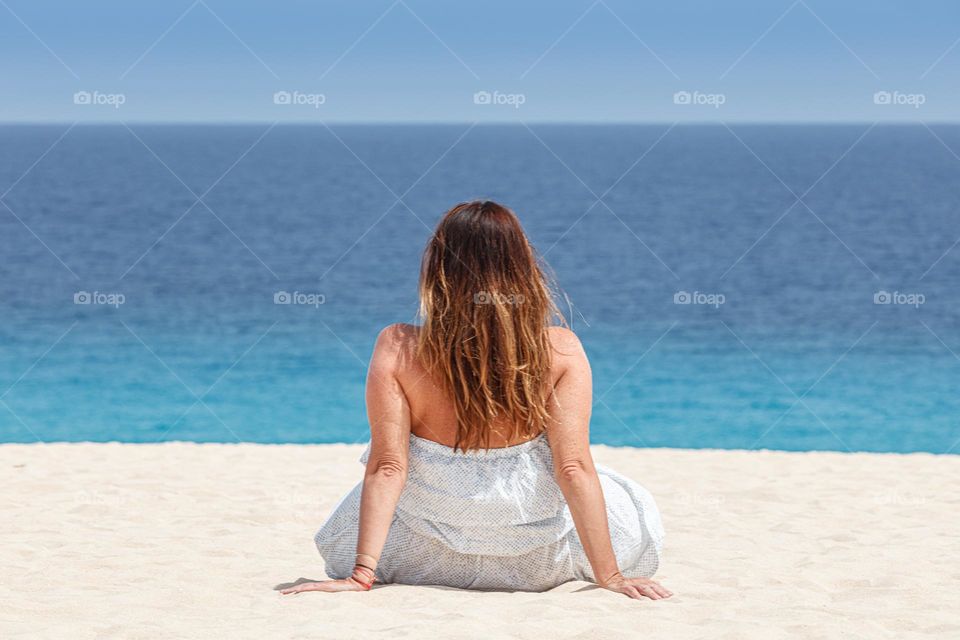 woman on bright mild sand staring at the ocean