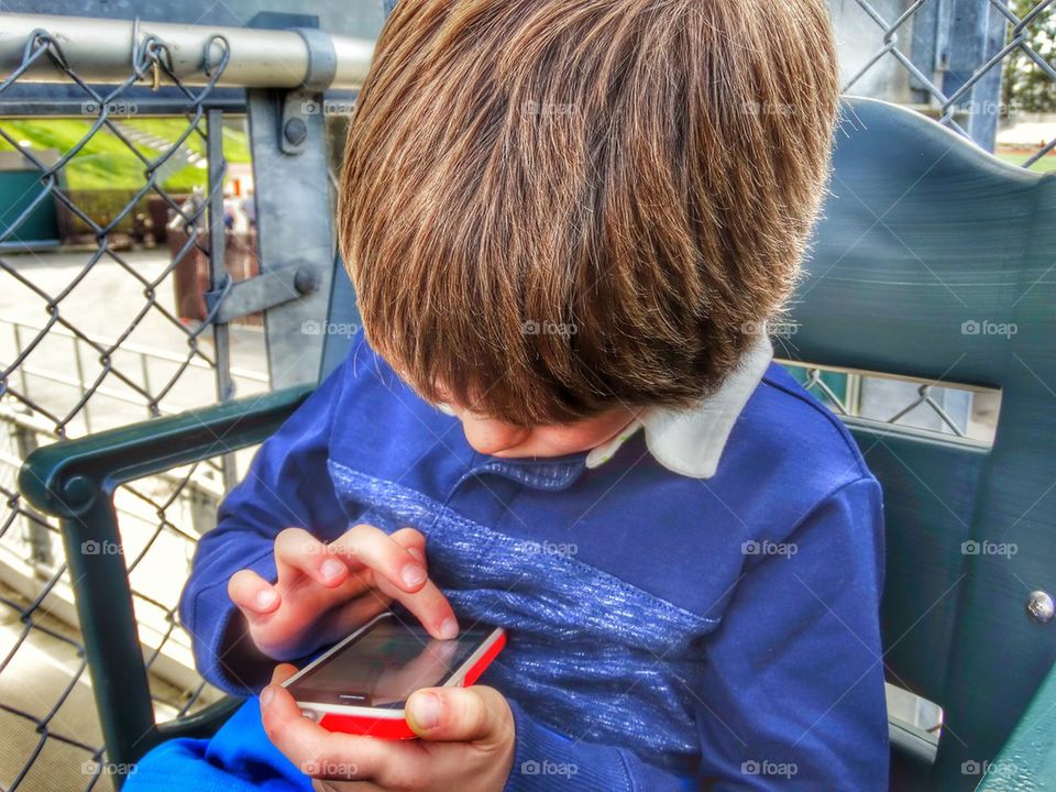 Young Boy Playing On A Smartphone. Child Playing With Parent's Smartphone
