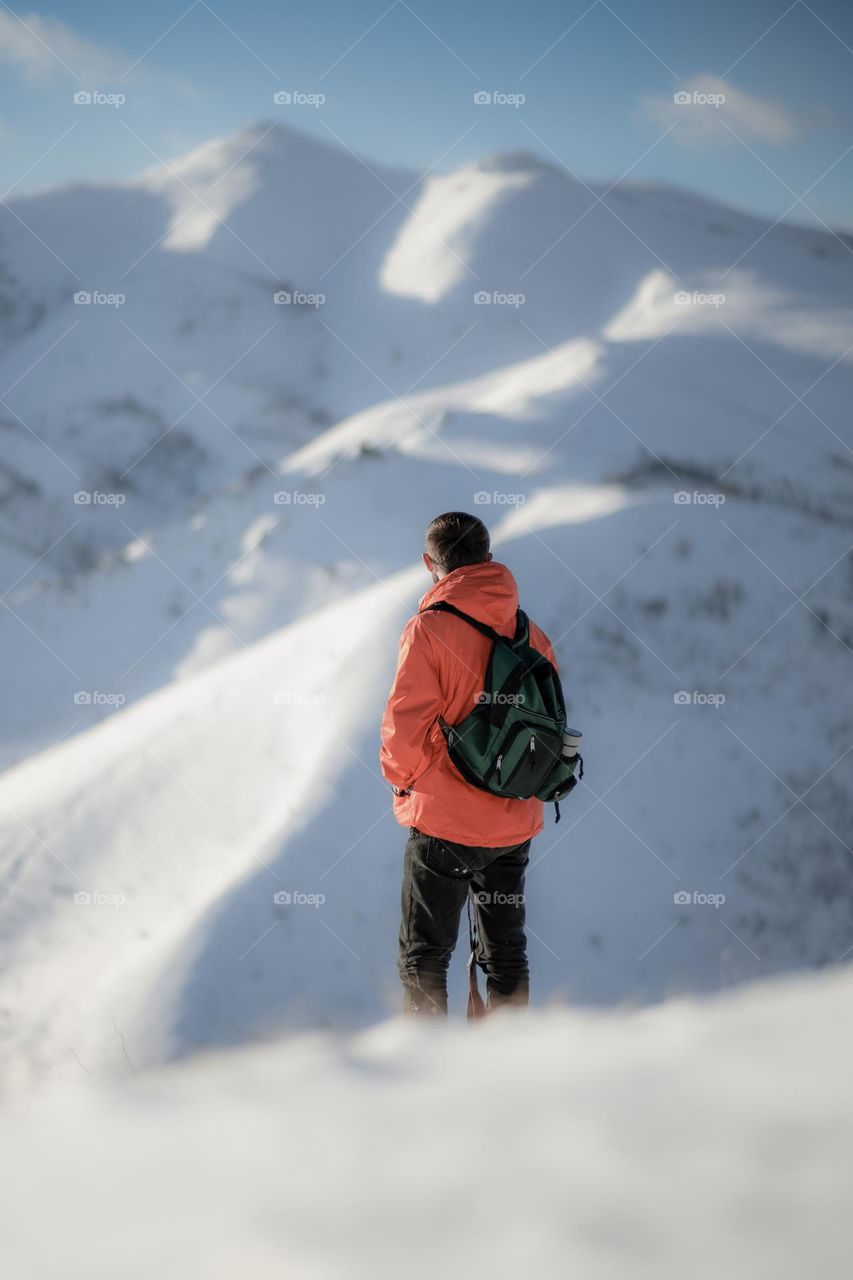 Male hiker looking at the view from the peak of a mountain in the wintertime .