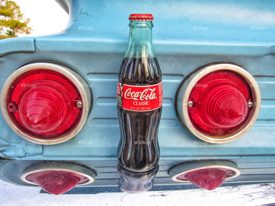 Coca-Cola bottle sitting on bumper or vintage car