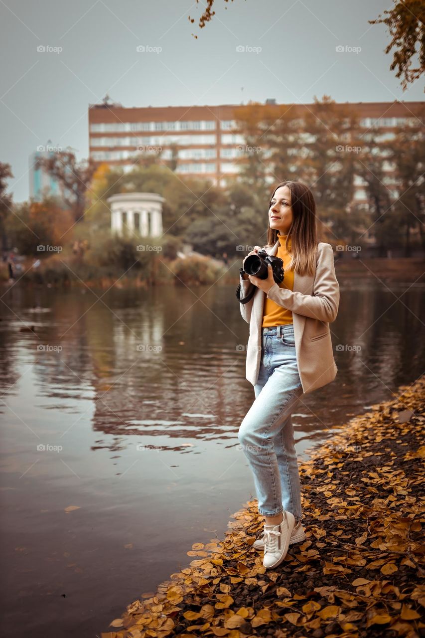 A young girl photographer walks in the autumn park by the lake, Life Style casual style
