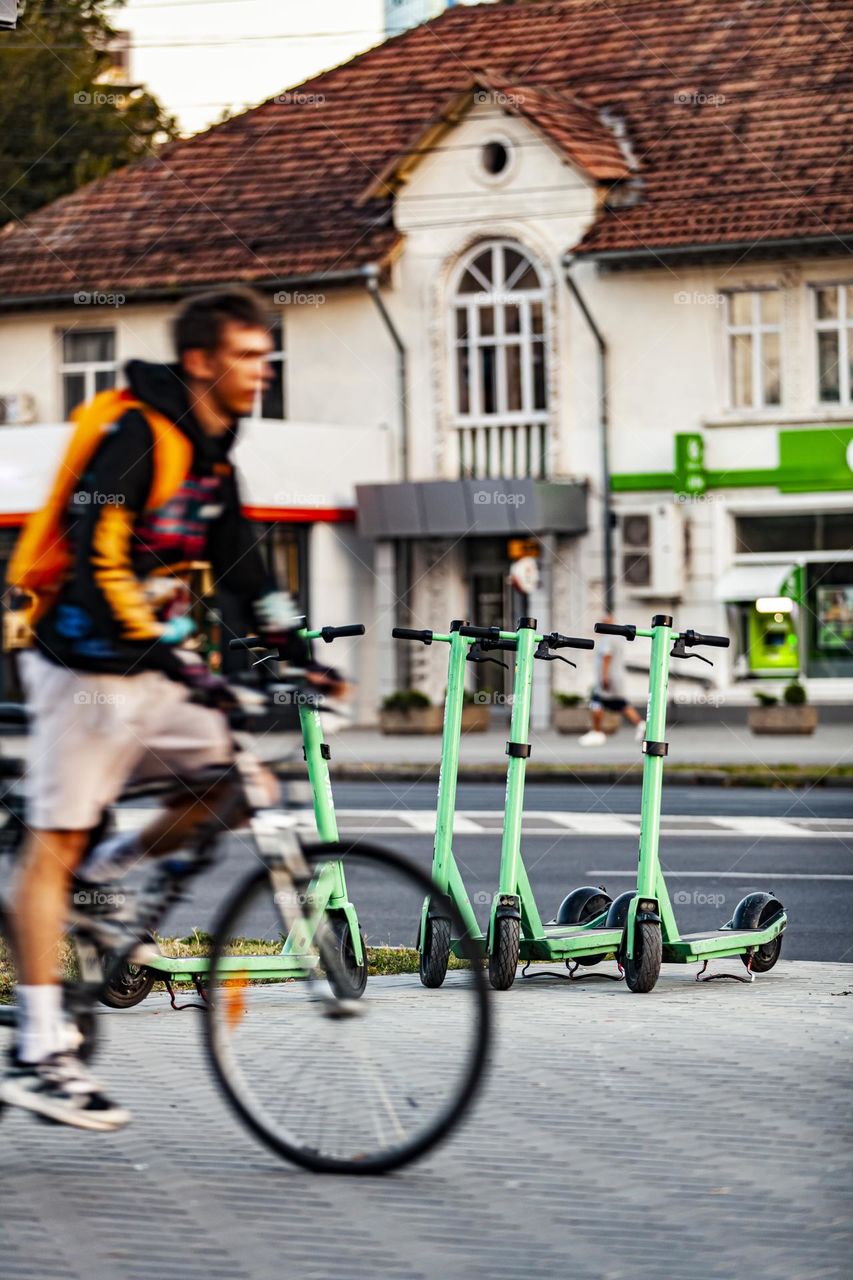 Movement and statics. Electric scooters and bicycle at sunset.