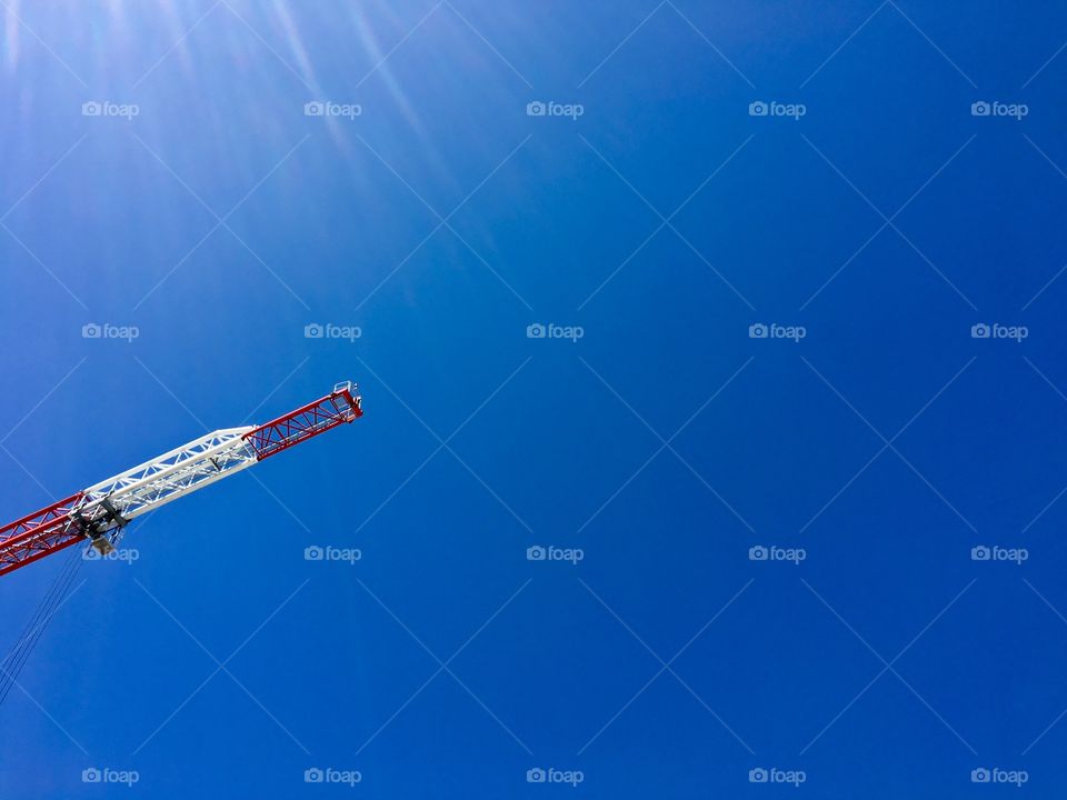 Construction crane high in the sky against vivid blue sky background minimalistic, room for text 