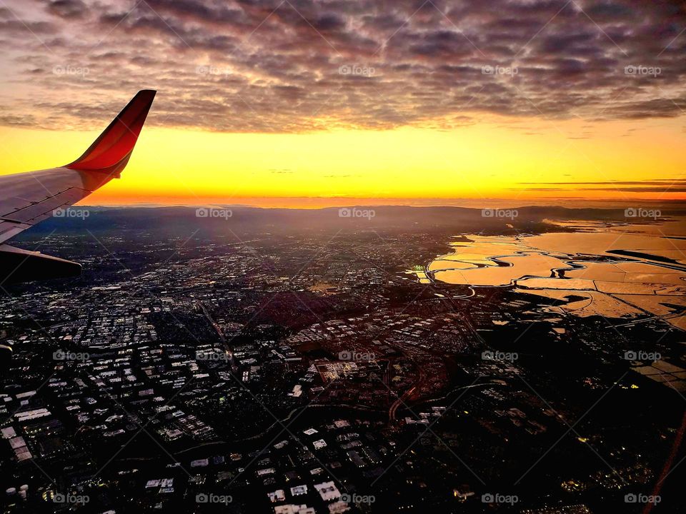 A brilliant orange sunset illuminates the southern end of the San Francisco Bay and the cloud cover above