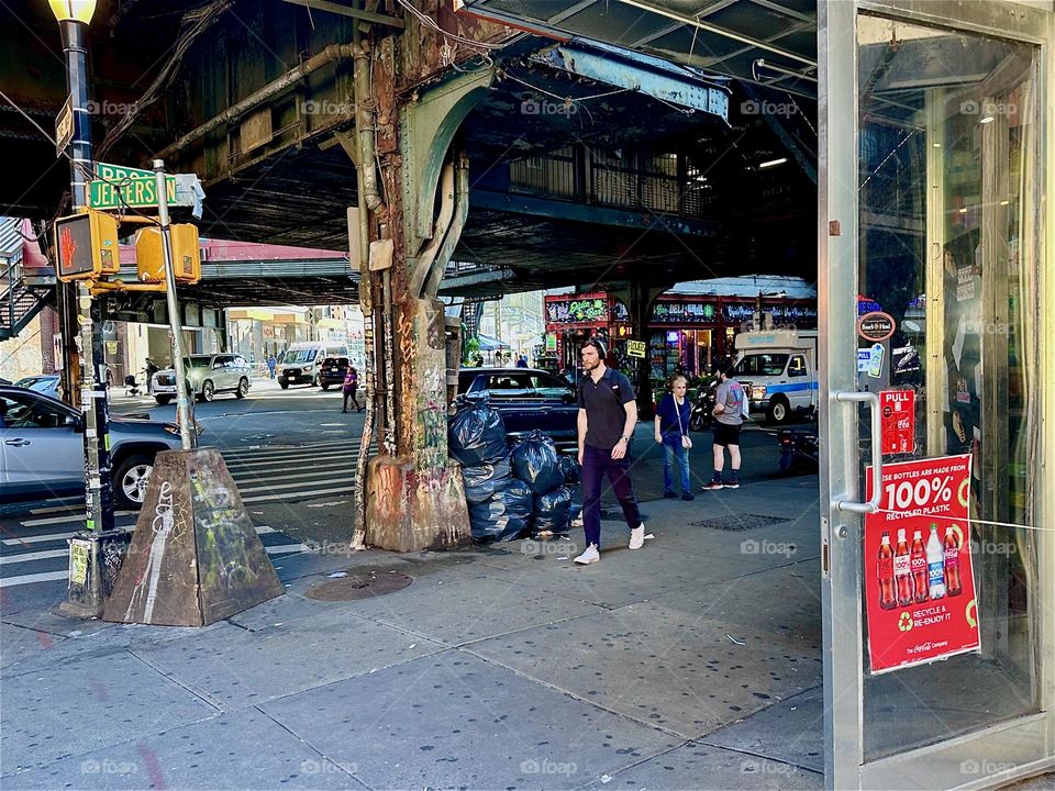 This is the intersection of “Jefferson St”, “Broadway” and “Myrtle Ave” in “Bushwick”, Brooklyn underneath the “M” train overpass at the “Myrtle Ave” station, a rather busy area nearly 24 hours a day. 2024. Hypnotic Productions