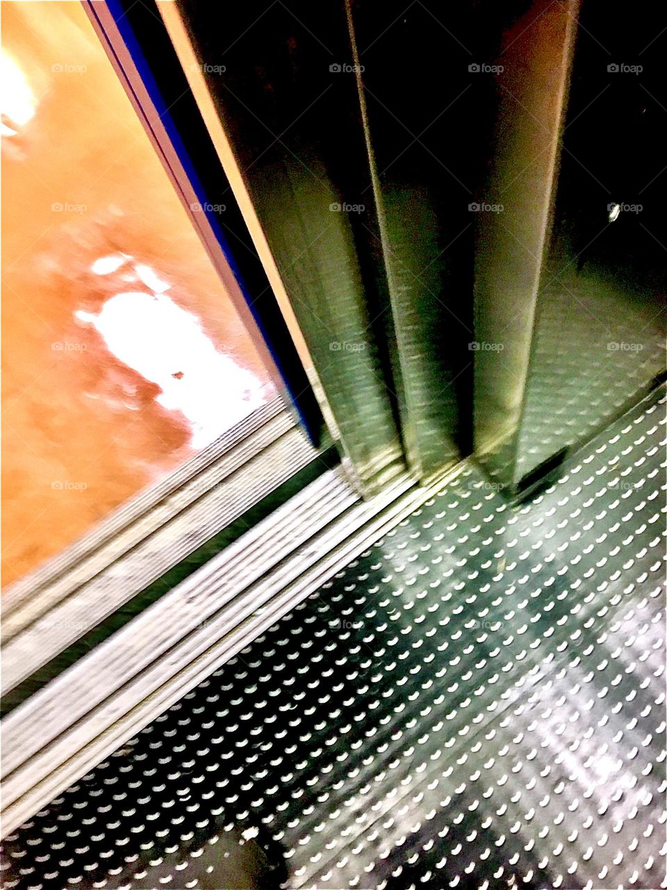 An urban detail from the interior of a subway station is this sparkling clean silver metallic floor next to an elevator door that reflects back whatever or whoever rests on its surface. 2021. Hypnotic Productions