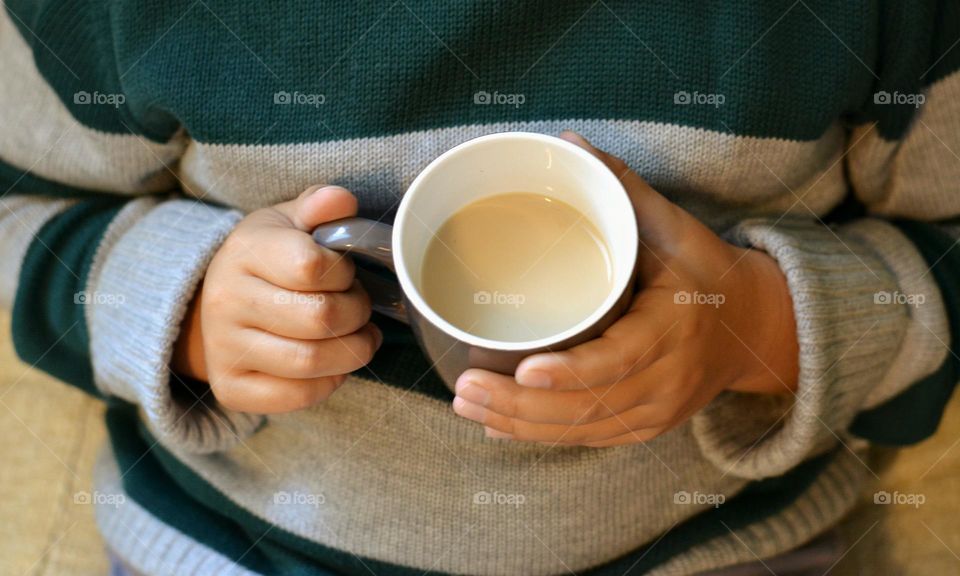 cup of coffee with milk in the hand child cozy winter