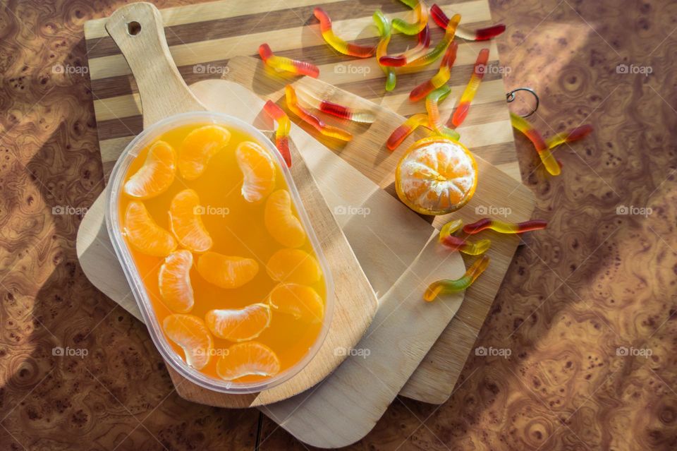 Delicious orange jelly with tangerine slices in a container and jelly worms.
