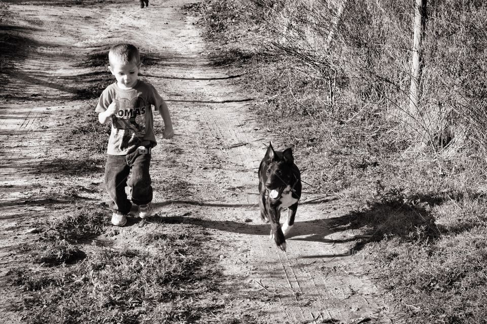 Boy walking with dog on dirt road