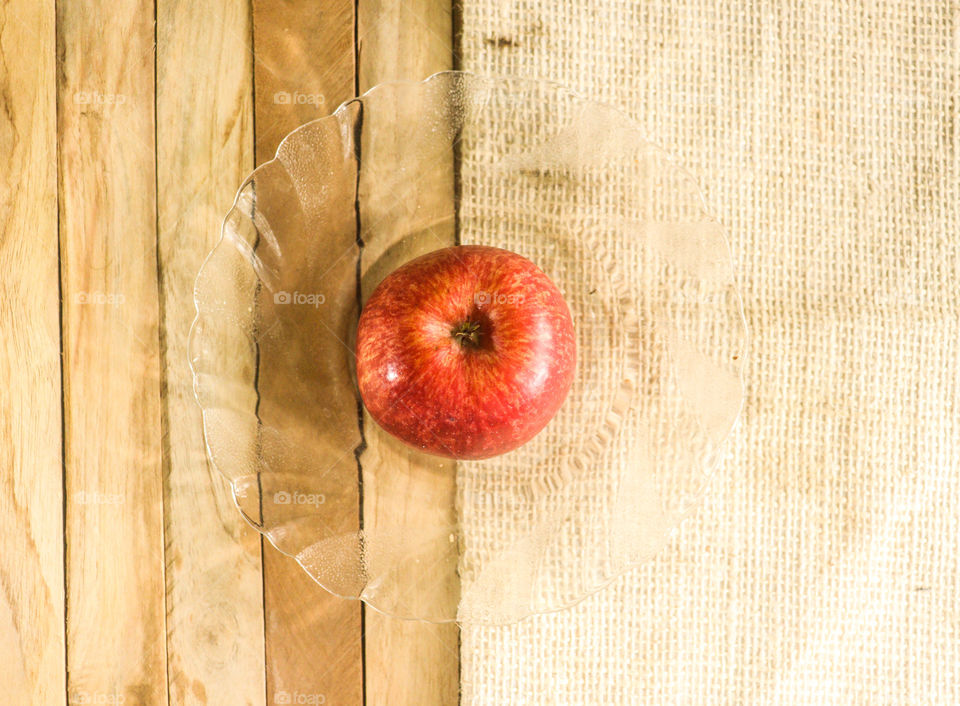 singal apple with glass plate wood background