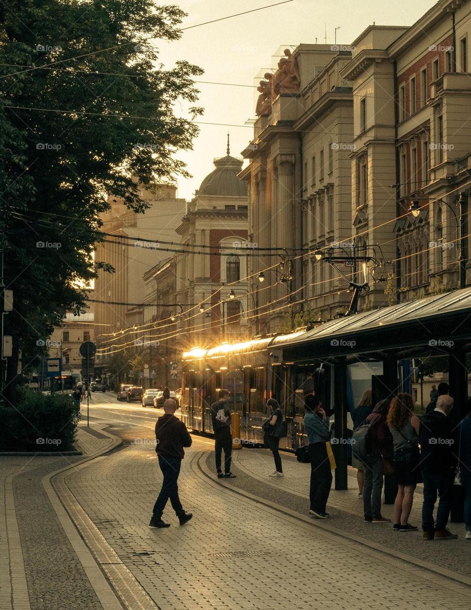 people are waiting for a tram on a beautiful street in Krakow